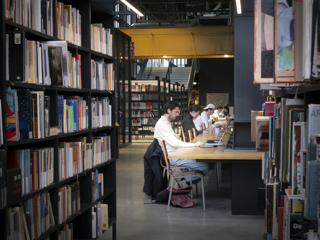 Estudantes em biblioteca; imagem ilustrativa que não retrata prova do Enem 2026. Foto: Fer Troulik/Unsplash.
