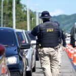 Policial rodoviário federal realiza fiscalização de veículos em rodovia durante operação de segurança